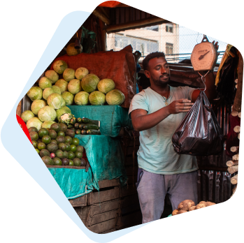 A fruit and vegetable vendor weighs a bag of produce for a customer.